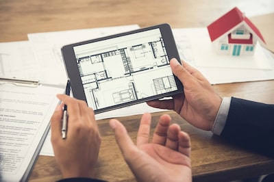 2 people look at a floor plan on a tablet