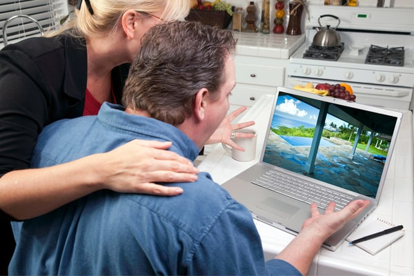 couple look at house picture on their laptop in the kitchen and exclaim