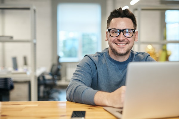 man with glasses at laptop smiling