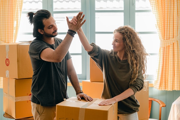man and woman high five in new home with boxes around them